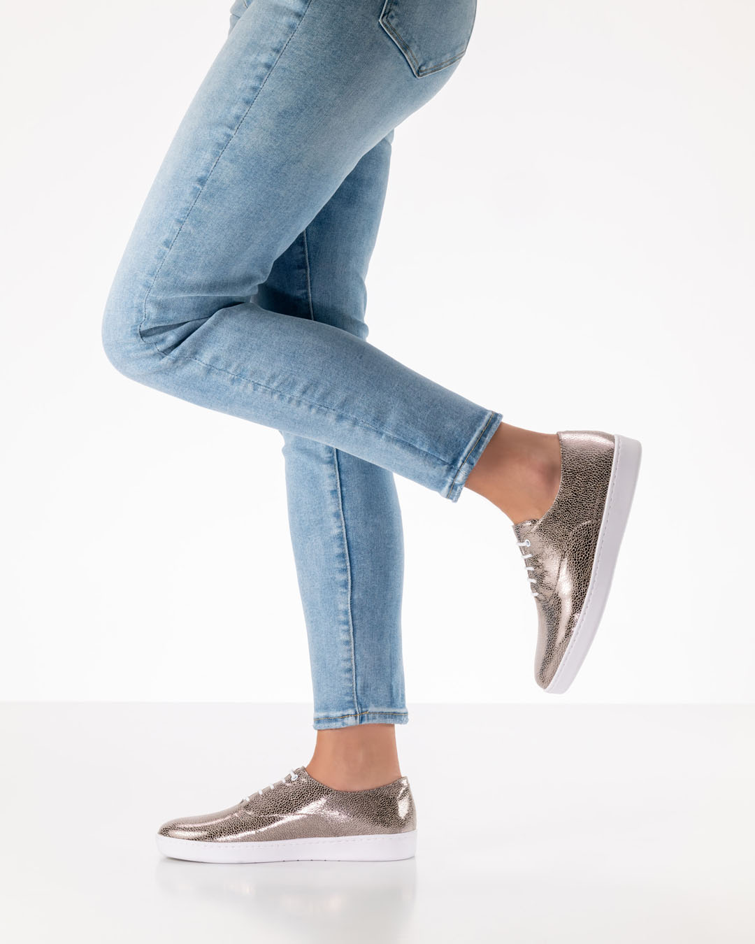 Les jambes d'un mannequin de chaussures de danse, vêtues d'un jean clair et chaussées de chaussures de danse à lacets couleur platine, dotées d'une semelle en PU blanche