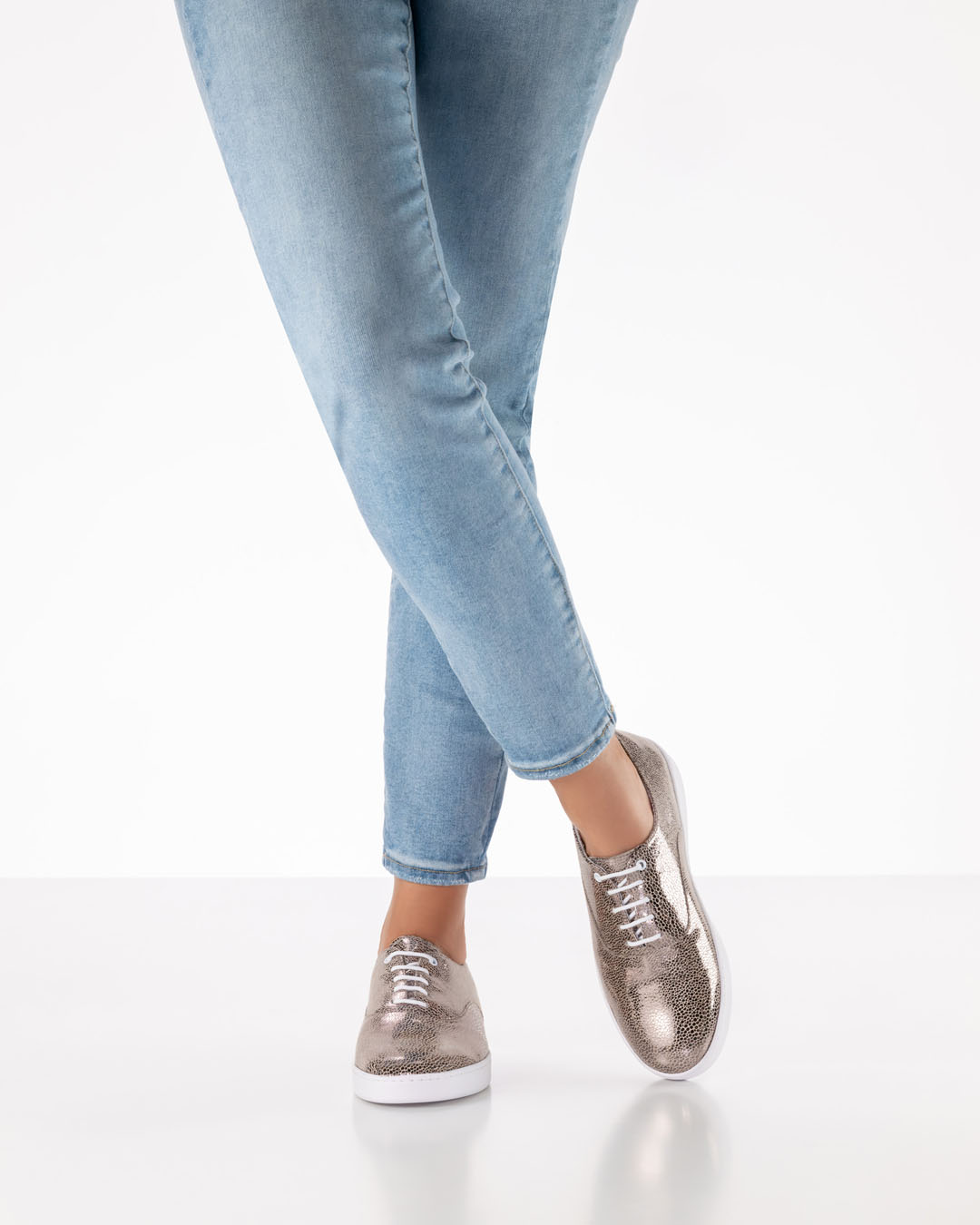 Chaussures de danse brillantes couleur platine, à lacets, avec une semelle blanche, de la marque Werner Kern, portées avec un jean clair