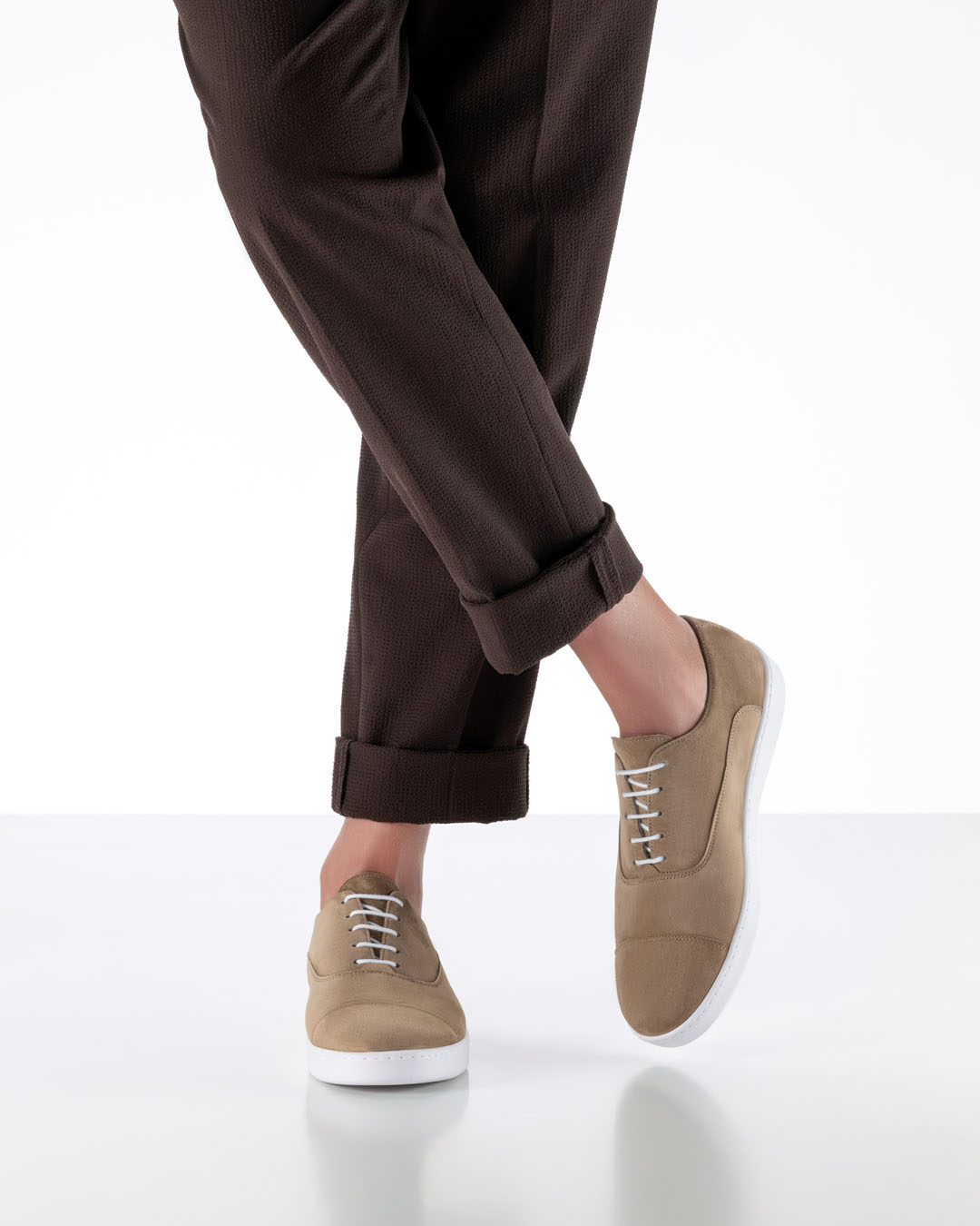 Chaussures de danse pour homme en cuir beige et semelle de basket blanche, portées par Werner Kern avec un pantalon en tissu marron foncé