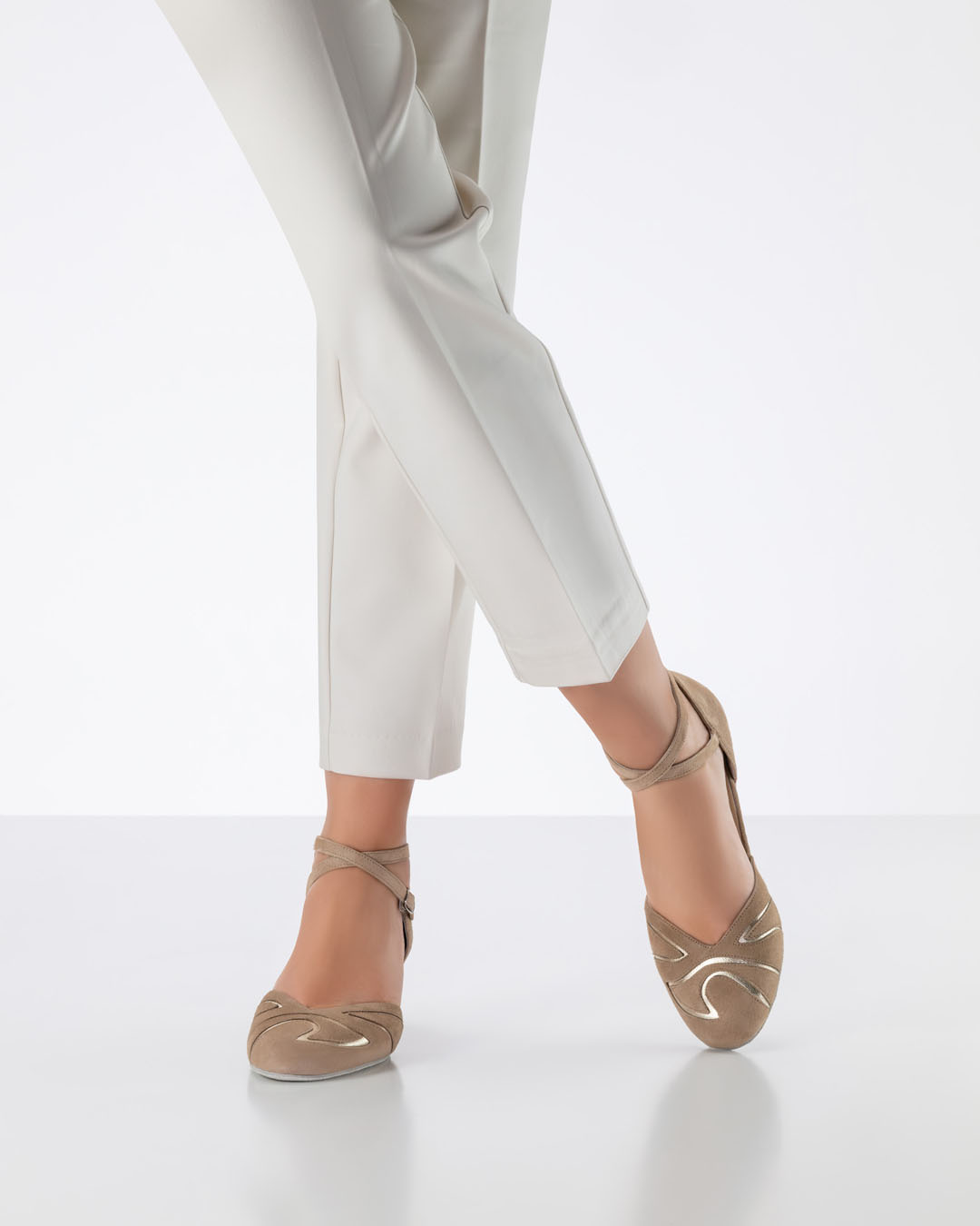 Un mannequin vêtu d'un pantalon beige clair croise les jambes et porte des chaussures de danse beiges à bout fermé de la marque Werner Kern
