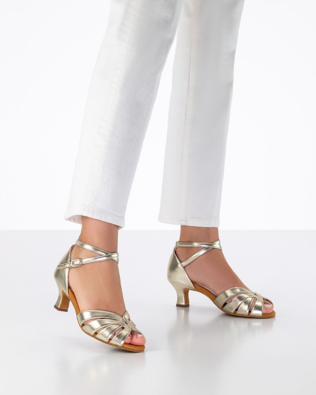 Le mannequin porte un jean blanc et des sandales de danse dorées à talons évasés de 5 cm