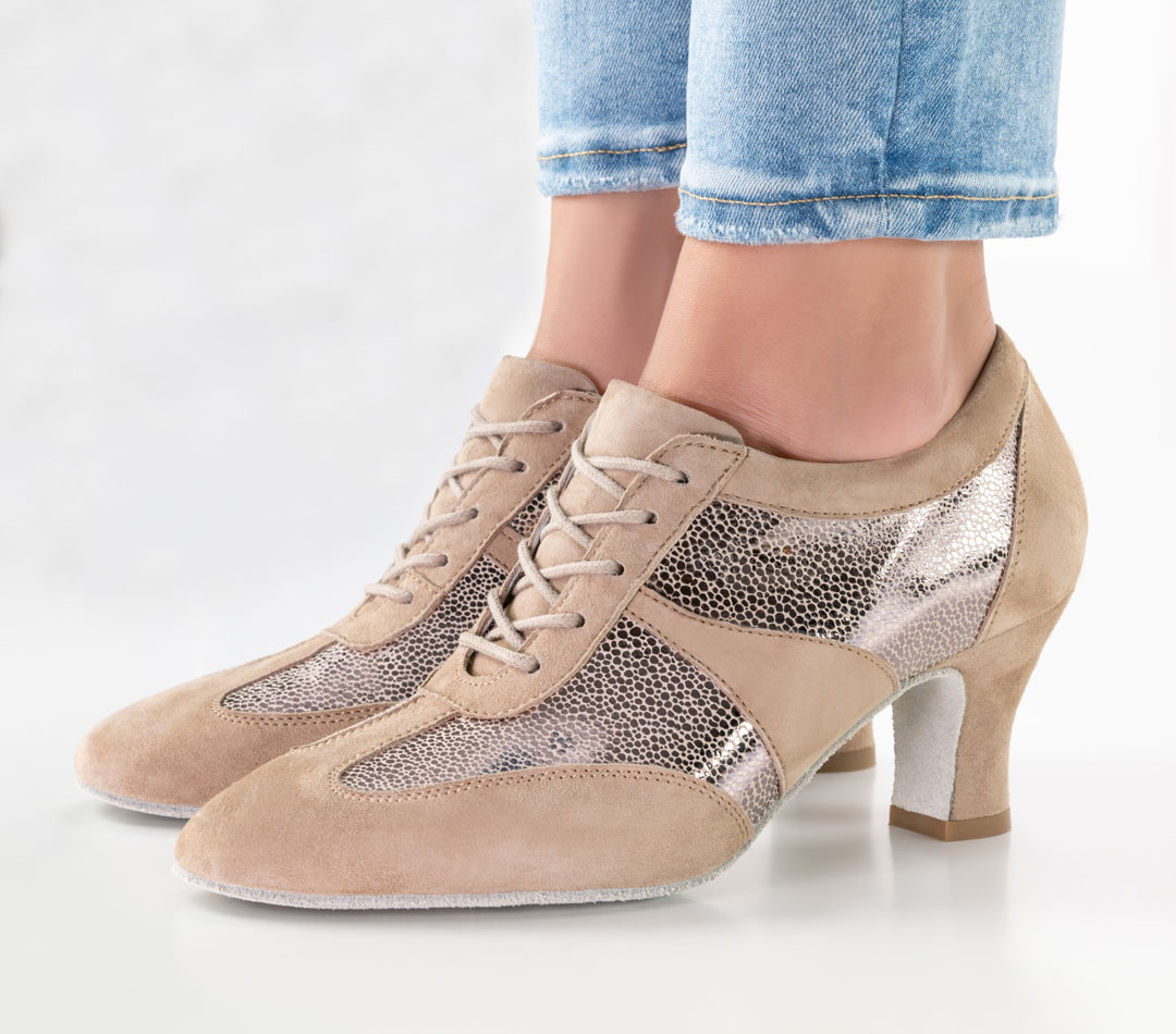 Gros plan sur un mannequin portant un jean et des baskets de danse beiges à lacets, dotées d'un talon bloc de 6 cm
