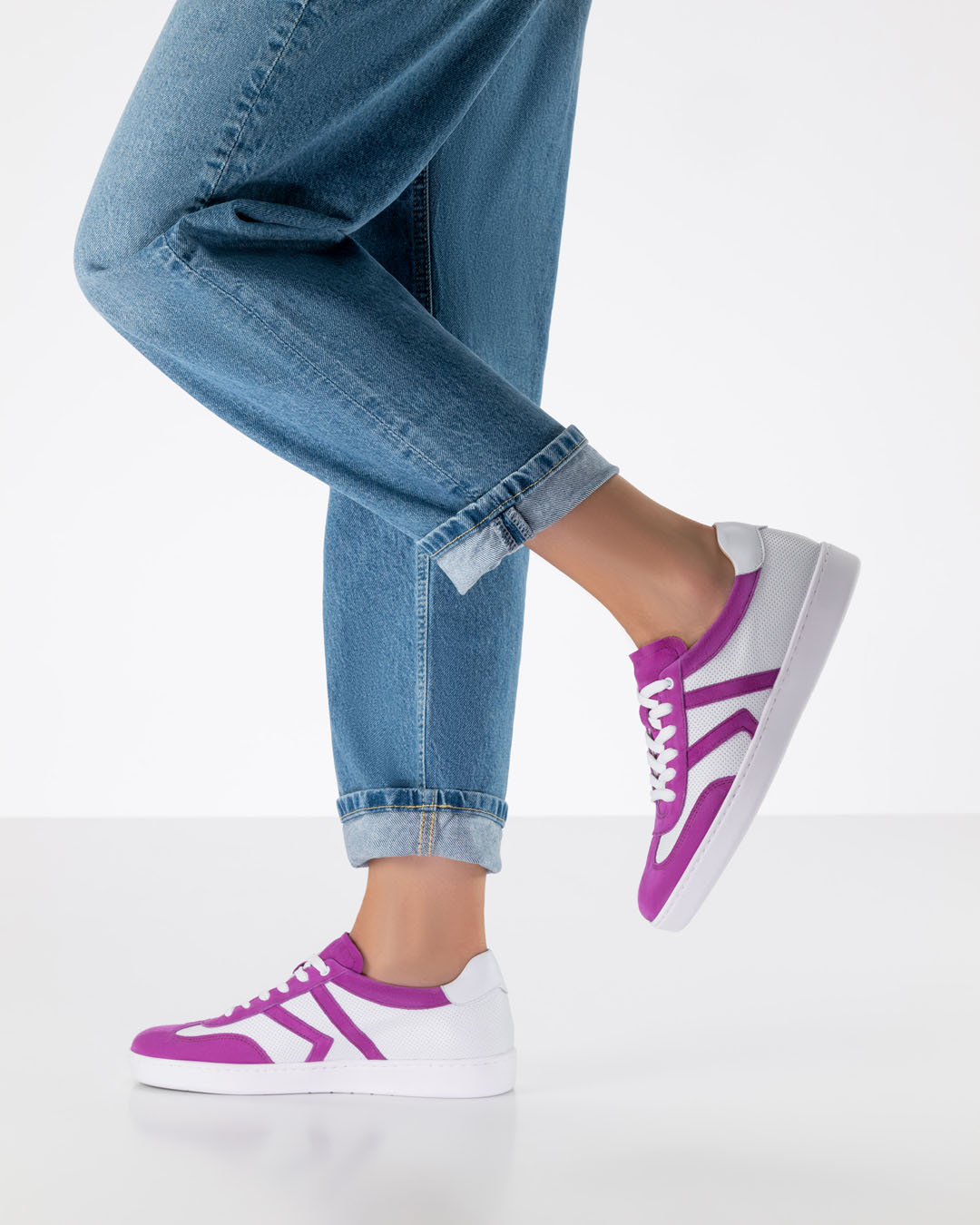 Modèle composé d'un jean ample et de baskets de danse en cuir blanc avec des empiècements roses