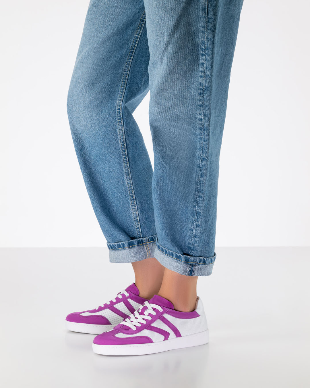 Les jambes d'un modèle de chaussures de danse, vêtues d'un jean à la coupe décontractée et de baskets de danse en cuir blanc et rose, dotées d'une semelle en PU blanche