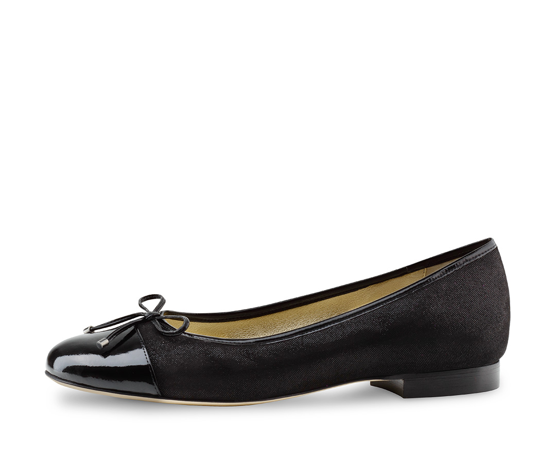 Une femme porte des ballerines en velours noir brillant.