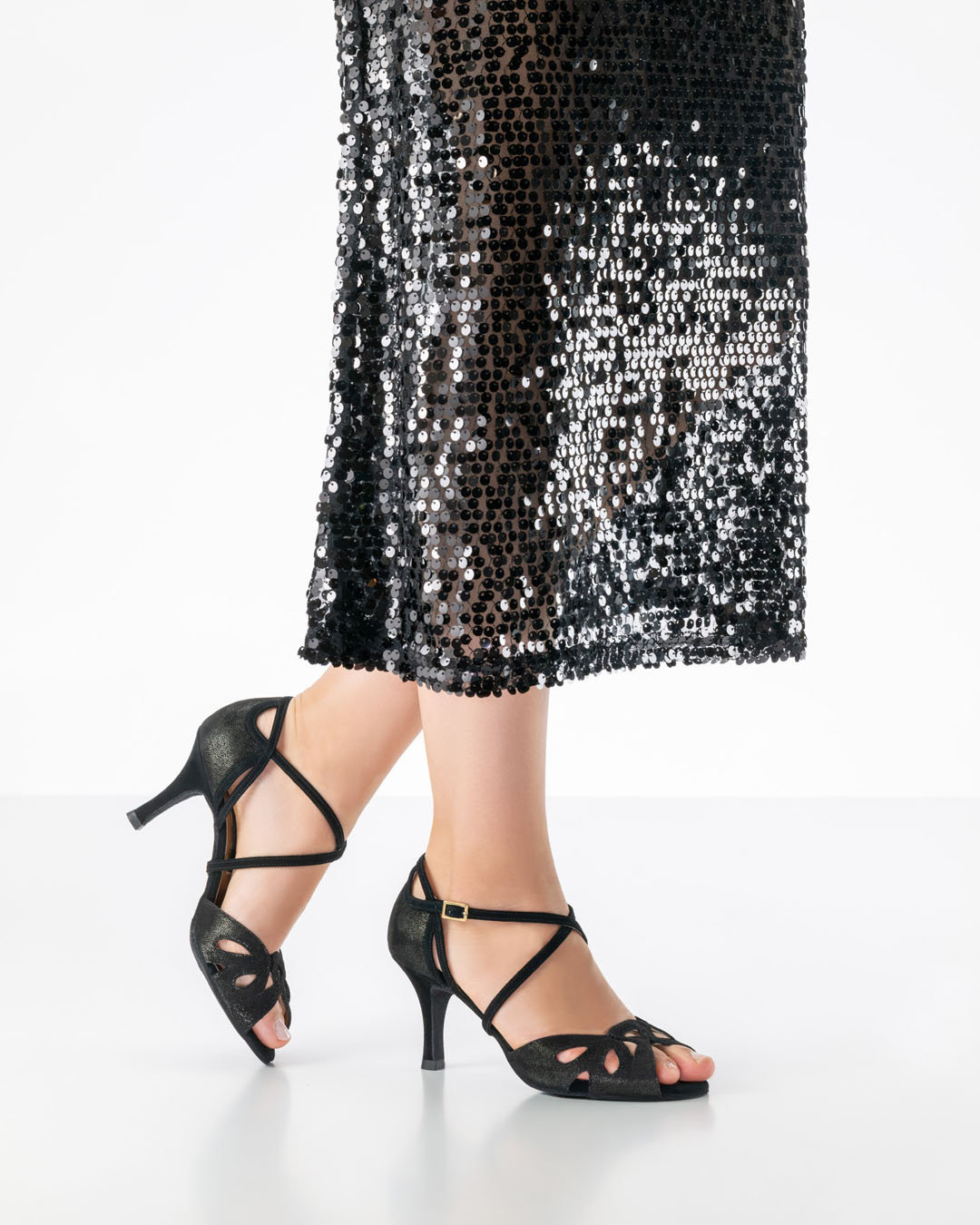 Elora - chaussure de danse ouverte, d'un noir chatoyant, avec un talon de 7 cm de la marque Nueva Epoca, portée avec une longue robe noire à paillettes