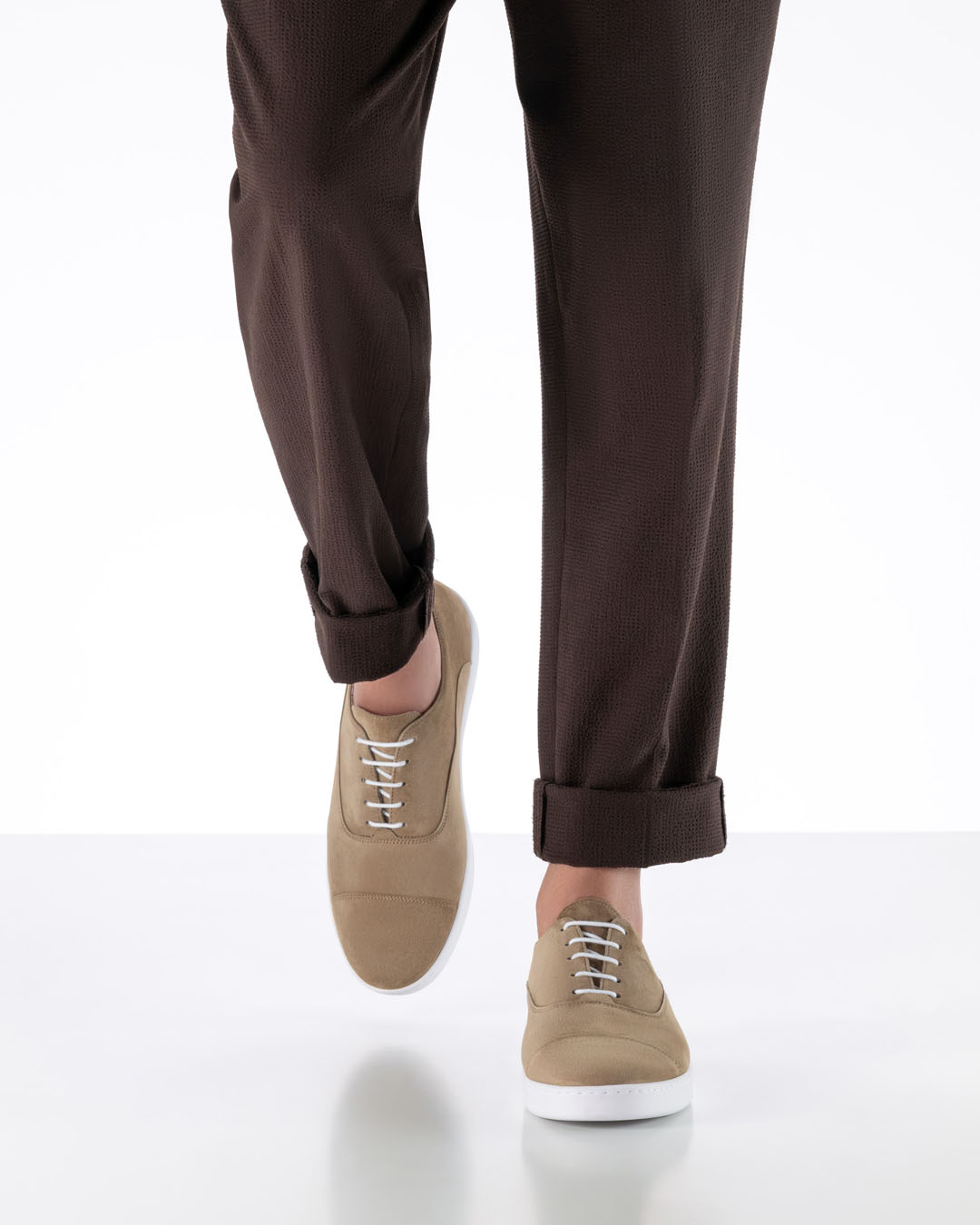 Le mannequin s'avance vers la caméra et porte des chaussures de danse beige clair dotées d'une semelle plate de type basket blanche.